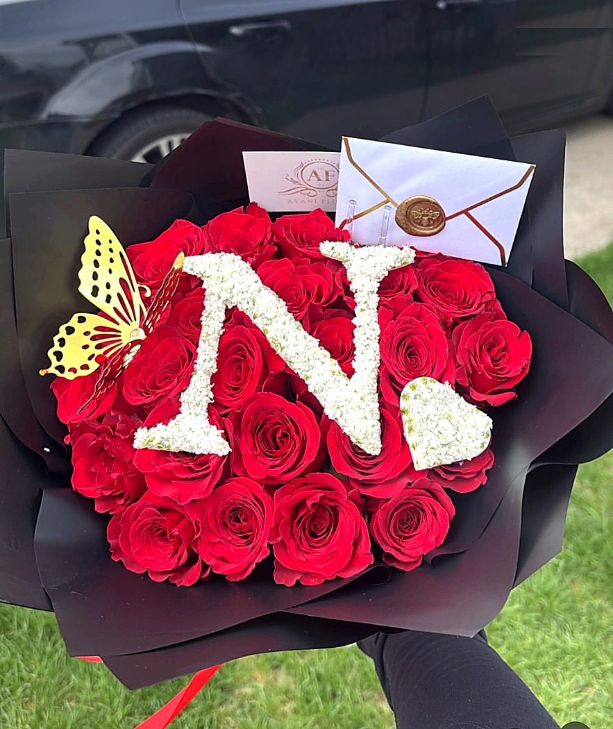 Custom initial bouquet shaped around the letter N in white flowers over red roses.
