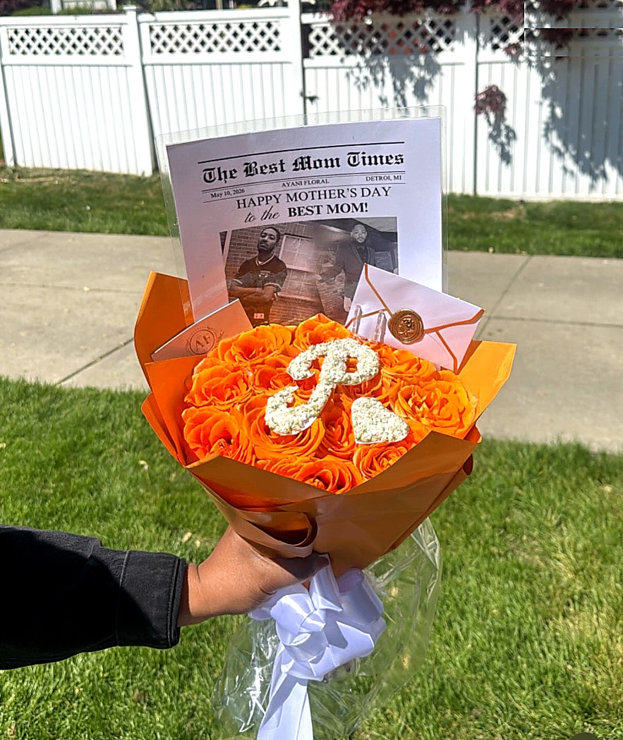 Orange graduation bouquet with custom floral initial and keepsake insert.